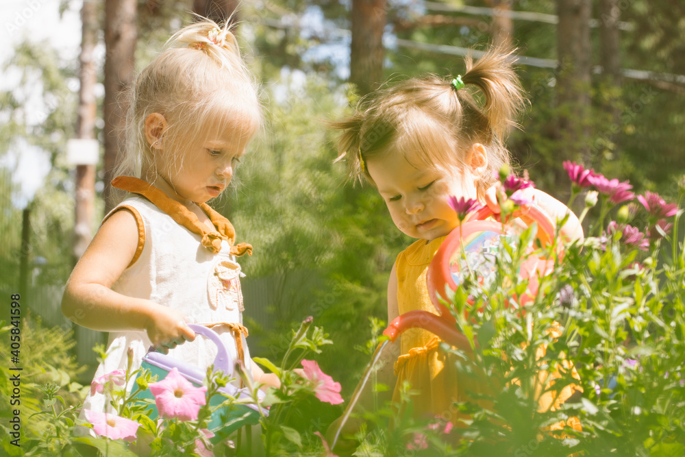 Two little girls sisters watering flowers Two little girls sisters watering flowers