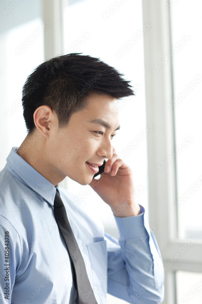 Portrait of young businessman talking on cell phone in office Portrait of young businessman talking on cell phone in office