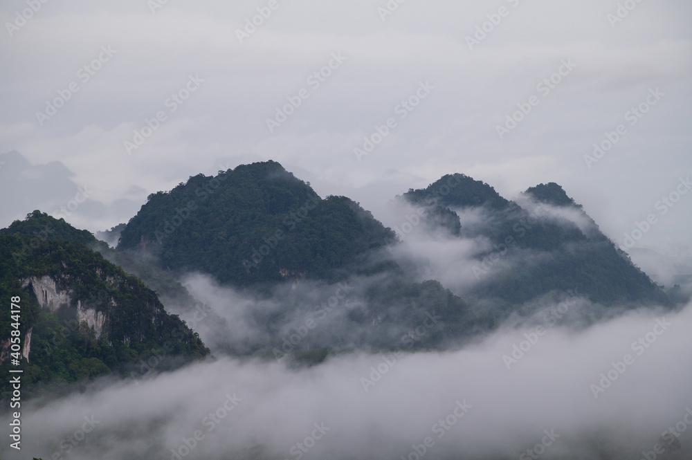 Mountain range with visible silhouettes through the morning colorful fog with cloud sky
