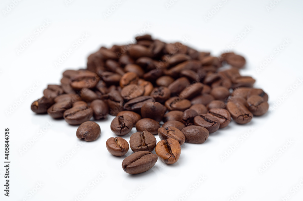 Dark, roasted coffee beans pile on a white surface.
Dark, roasted coffee beans pile on a white surface.