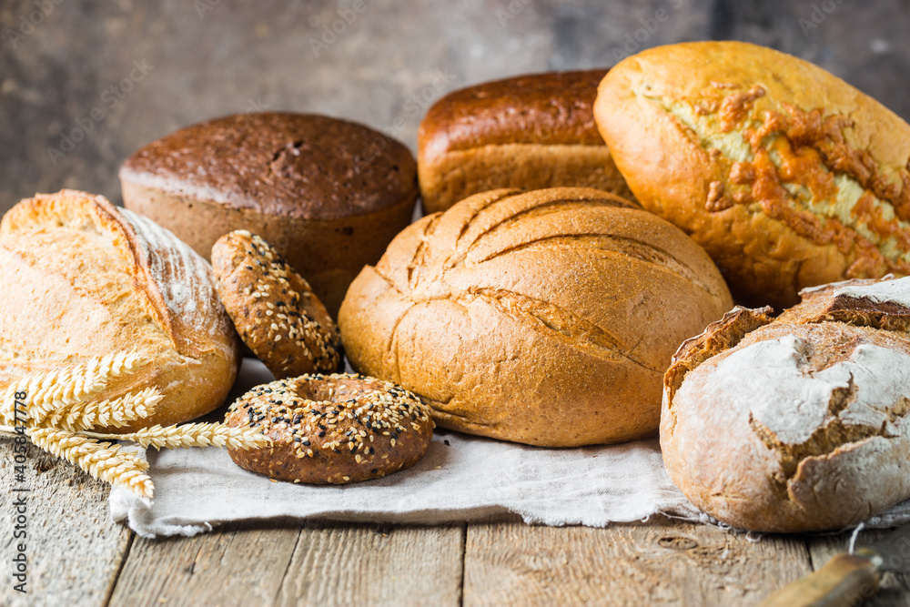 Assortment of fresh baked bread and buns on wooden table background