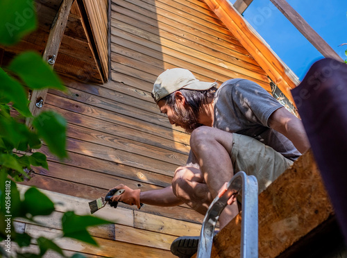 Man painting wooden wall of house outdoors