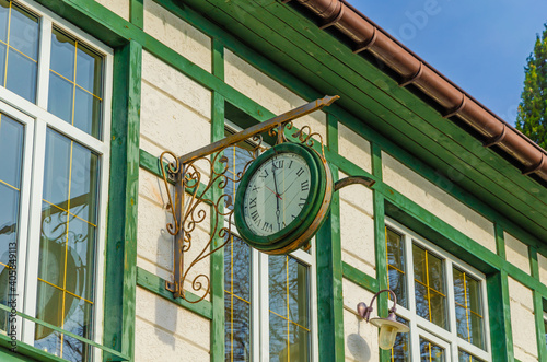 Round clock on the wall of a wooden house.
