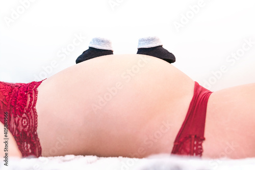 Pregnant woman with a pair of baby shoes on white background