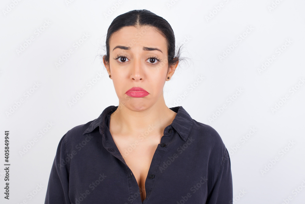 young beautiful Arab woman wearing gray dress against white studio wall crying desperate and depressed with tears on his eyes suffering pain and depression. Sad facial expression and emotion concept. young beautiful Arab woman wearing gray dress against white studio wall crying desperate and depressed with tears on his eyes suffering pain and depression. Sad facial expression and emotion concept.