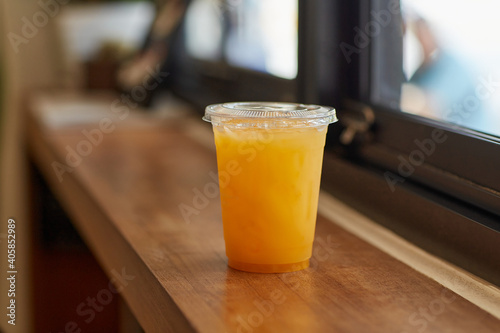 DISPOSABLE PLASTIC CUP DRINKS   plastic cup of tea for takeaway place on glass counter table in cafeteria. Close up and selective focus