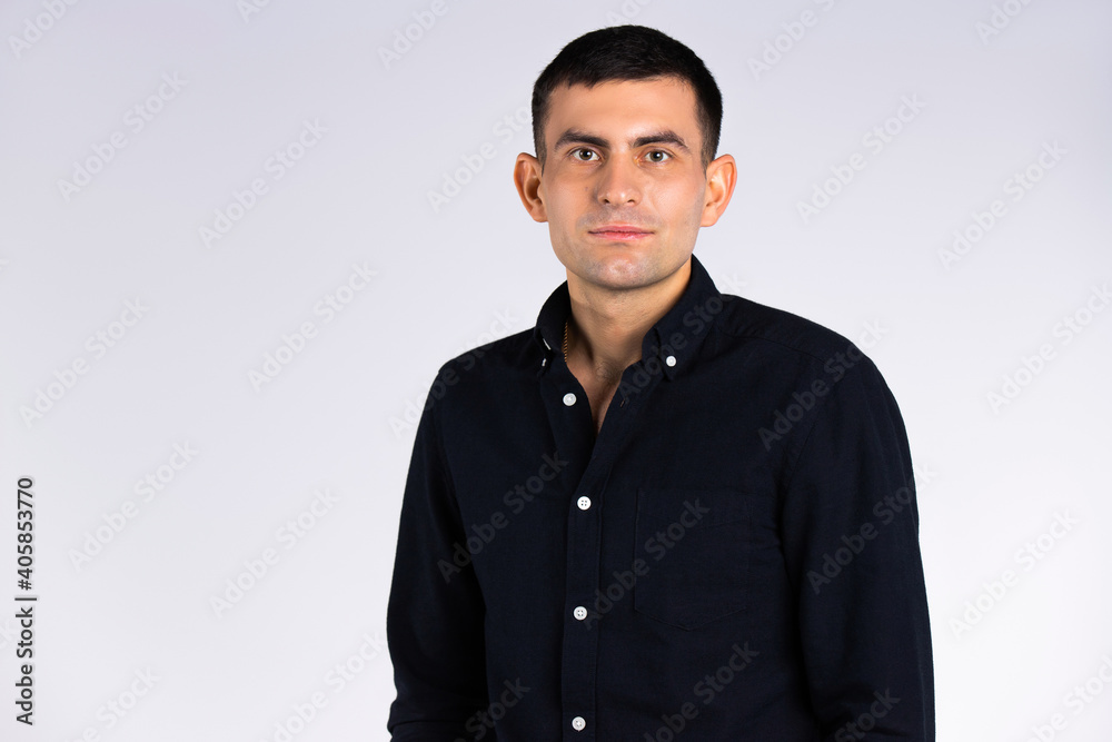 An elegant and stylish man in a black shirt on a white background in the studio with empty side space. An elegant and stylish man in a black shirt on a white background in the studio with empty side space.