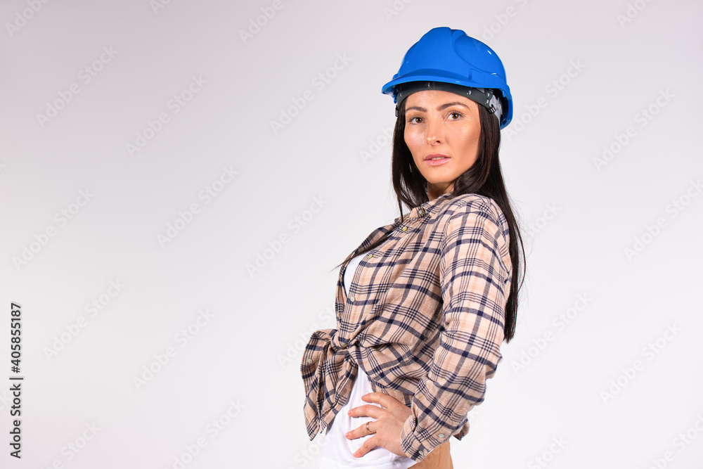 Portrait of young caucasian female engineer in blue hard hat posing against gray background with blank space. Portrait of young caucasian female engineer in blue hard hat posing against gray background with blank space.