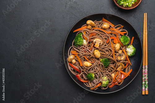 Vegan Stir fry with vegetables and mushrooms in black bowl. Close up view. Black slate background