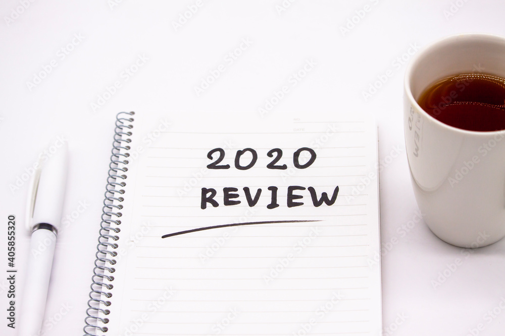 Notepad inscribed 2020 review with pen and tea cup on a white background Notepad inscribed 2020 review with pen and tea cup on a white background