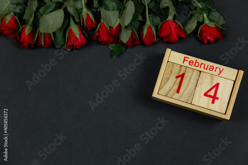 Red roses for the holiday on a dark background with wooden calendar ,. place for text for Valentine's Day