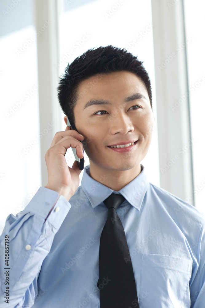 Portrait of young businessman talking on cell phone in office Portrait of young businessman talking on cell phone in office