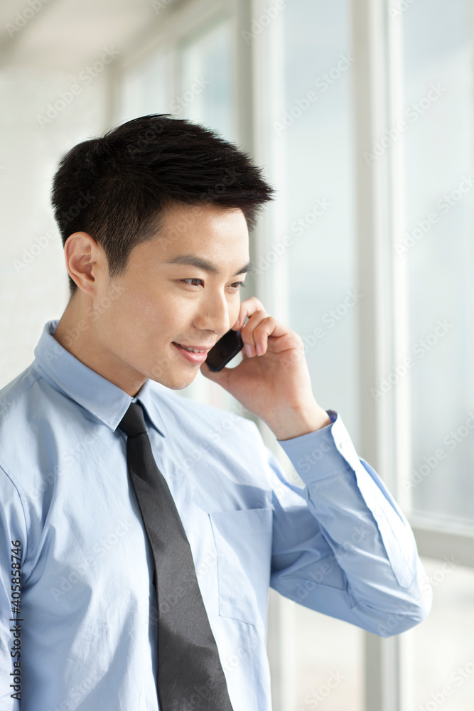 Portrait of young businessman talking on cell phone in office Portrait of young businessman talking on cell phone in office