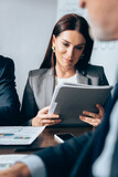 Businesswoman holding paper folder near investor on blurred foreground