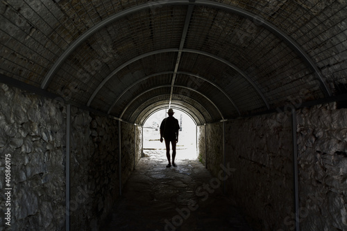 Silhouette of a man in a hat in a vaulted tunnel