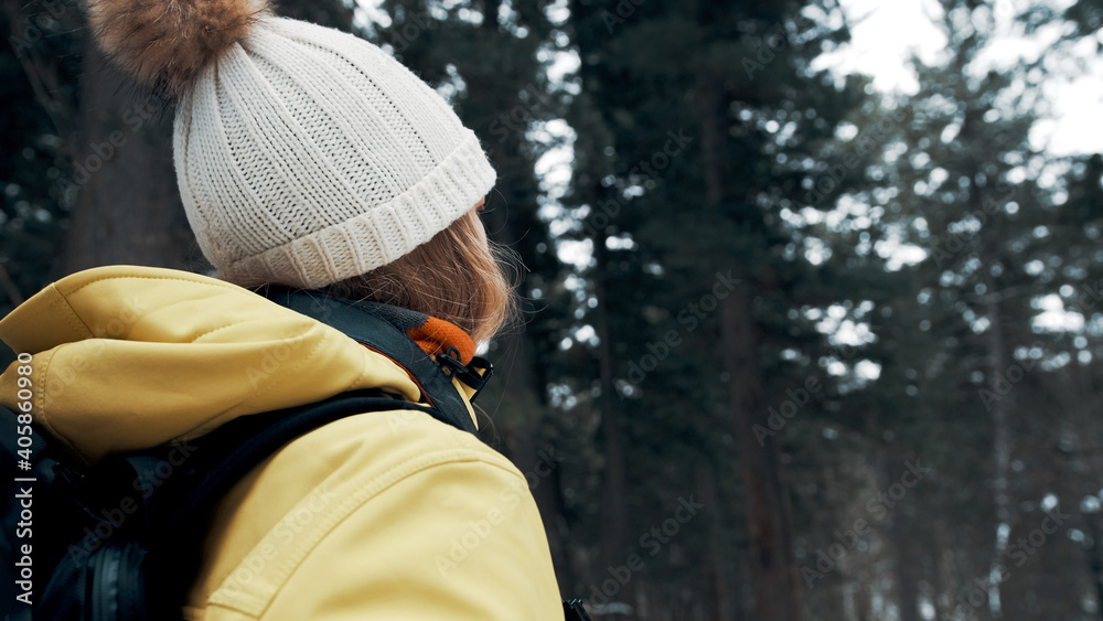 Fototapeta premium A girl with a backpack and a yellow anorak photographs the landscape on a professional camera