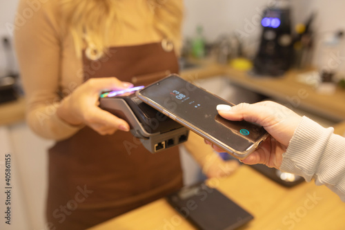 Close Up of a Woman Hand Holding a Smartphone with an NFC Payment Technology Used for Paying for Take Away Coffee in a Cafe.