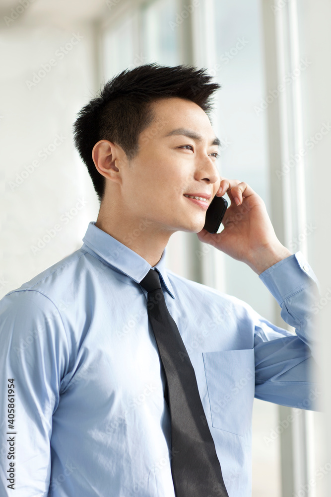 Portrait of young businessman talking on cell phone in office Portrait of young businessman talking on cell phone in office