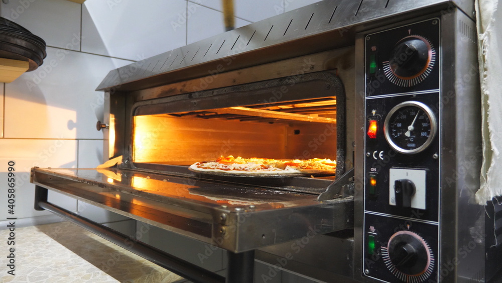 Male hand of cook opening the oven and putting uncooked dish at cuisine. Young chef sliding pizza using a shovel and closing a furnace at kitchen restaurant. Concept of preparing food. Slow motion Male hand of cook opening the oven and putting uncooked dish at cuisine. Young chef sliding pizza using a shovel and closing a furnace at kitchen restaurant. Concept of preparing food. Slow motion