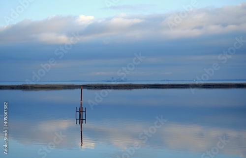 a pole in a calm lake with amsterdam in the mist in the netherlands