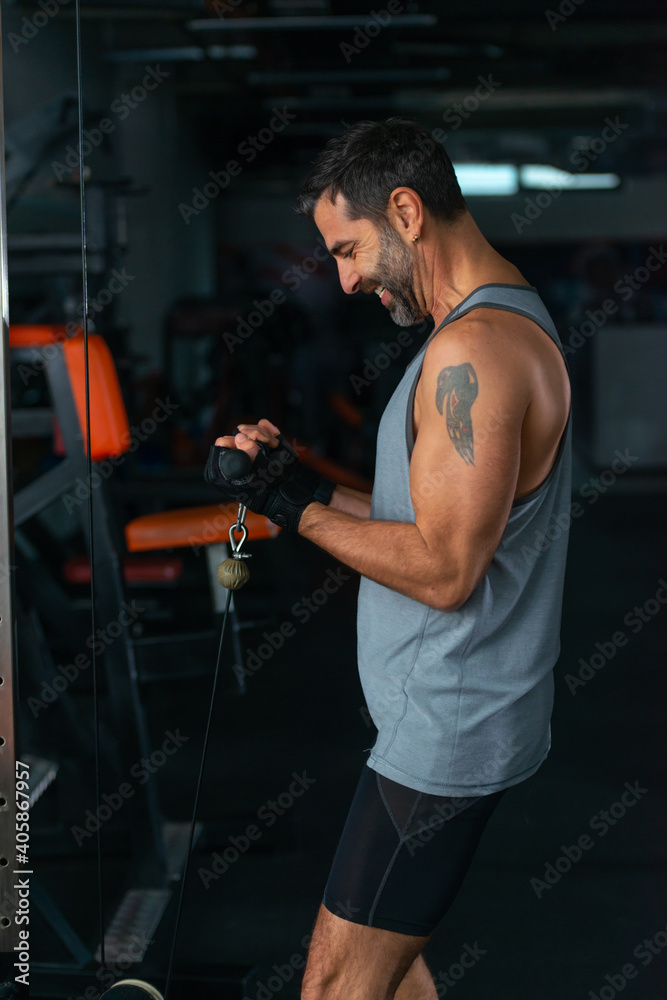 Bodybuilder doing underhand cable tricep pushdowns during his workout in the gym Bodybuilder doing underhand cable tricep pushdowns during his workout in the gym