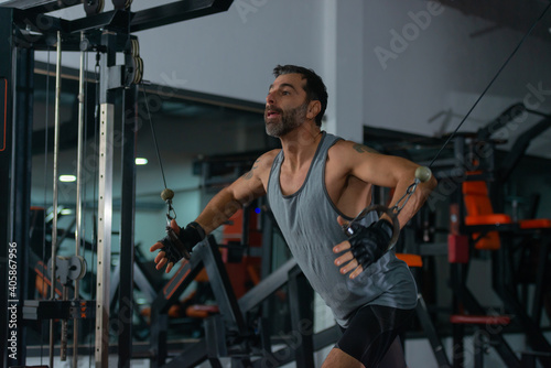 A mature man exercising in the gym by pulling the sling for upper-back exercises