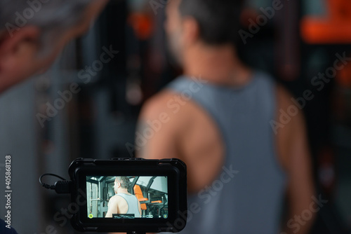Videographer making video of a mature man exercising in modern gym