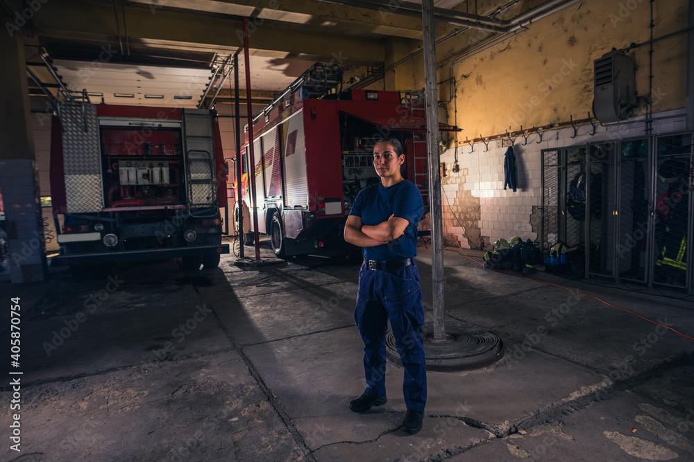 Portrait of female firefighter standing against firetruck at station