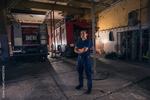 Portrait of female firefighter standing against firetruck at station © qunica.com