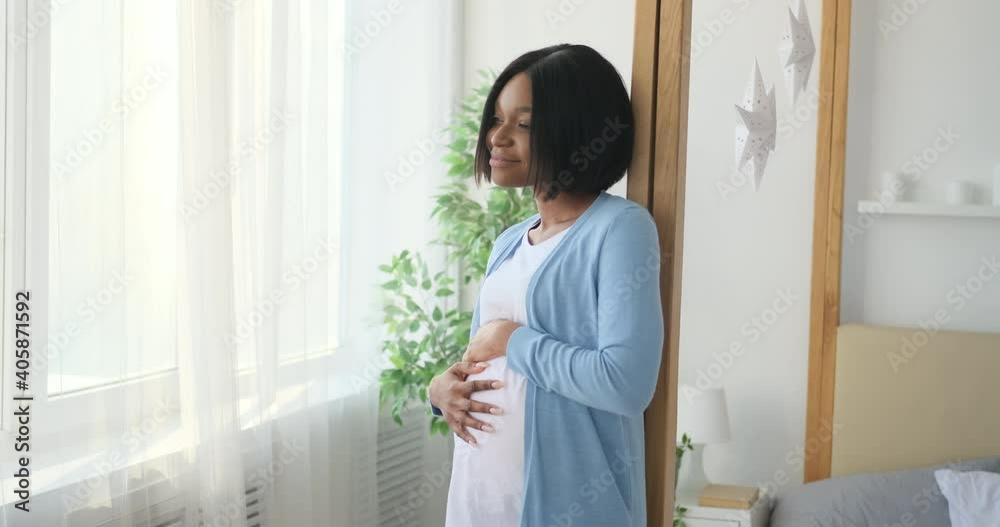 Happy african american woman caressing her pregnant belly at home Happy african american woman caressing her pregnant belly at home