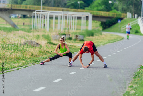 Young couple  warming up and stretching together in a park before running