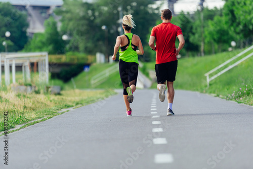Rearview of caucasian female and male running outdoors on a road