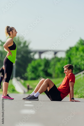 Young caucasian couple taking a break on the running road track and resting after running.