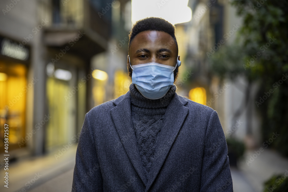 Young African businessman wearing mask for protection from corona virus outbreak walking outdoors. Young African businessman wearing mask for protection from corona virus outbreak walking outdoors.
