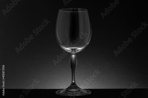 Copa de cristal vacía sobre fondo negro con iluminación posterior, en clave baja.