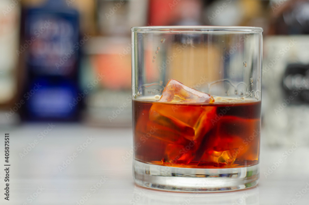Old fashioned glass with scotch whisky and ice cubes on the bar Old fashioned glass with scotch whisky and ice cubes on the bar