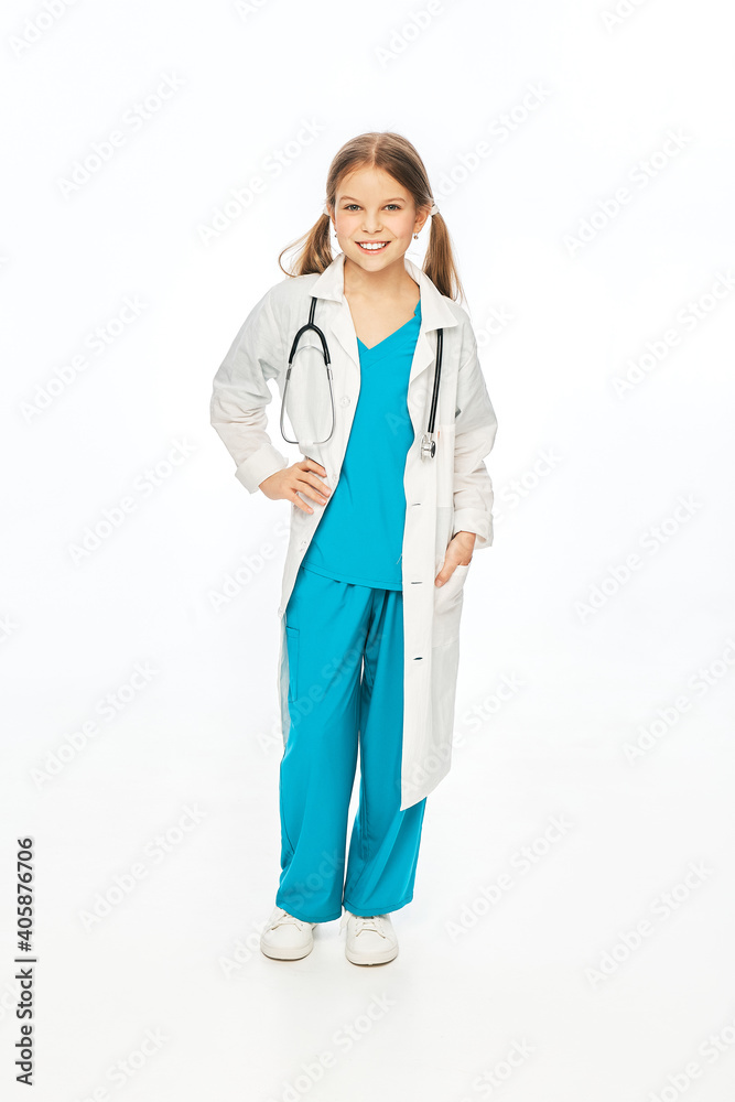 Child, future doctor. Cute girl wearing a medical outfit with toothy smile, looking at camera, full length. Isolated on white background Child, future doctor. Cute girl wearing a medical outfit with toothy smile, looking at camera, full length. Isolated on white background