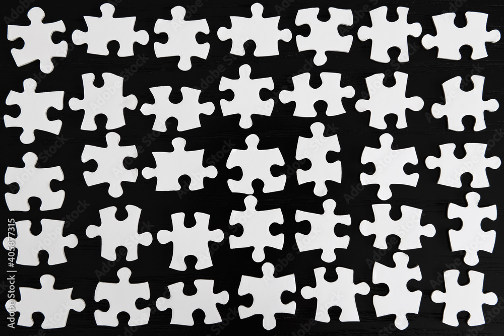 Naklejka premium Grid rows of white jigsaw puzzle pieces on a black table