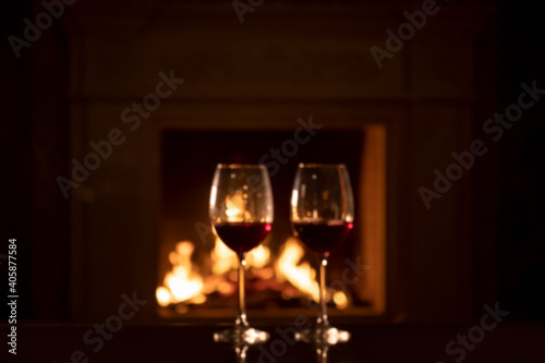 two glasses of red wine - romantic dinner against the background of a burning fireplace 