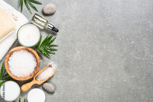Spa background. Spa product composition with natural cosmetic, towel, sea salt and alm leaves at stone table. Flat lay image with copy space.