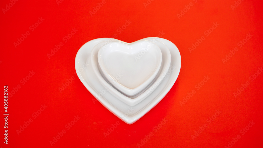 Heart form white plates on red background - Valentines day concept Heart form white plates on red background - Valentines day concept