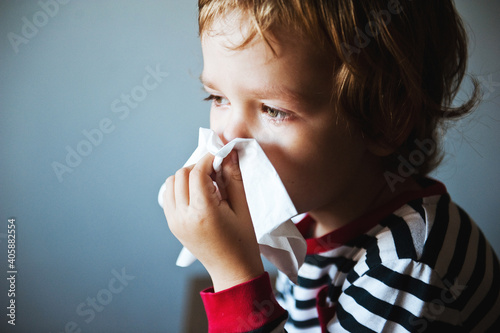 Canvas Print Cute little boy blowing his nose into a handkerchief.