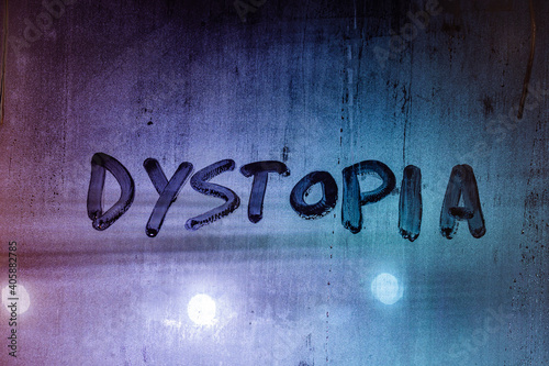 the word dystopia handwritten on wet window glass surface photo