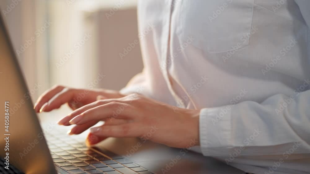 Close-up woman working on a laptop against the sunset. Concept of remote work.