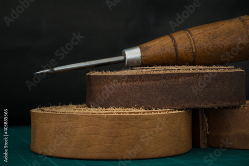 Fotomural Closeup shot of a wooden stitching awl and genuine leather rolls on a craftsman'