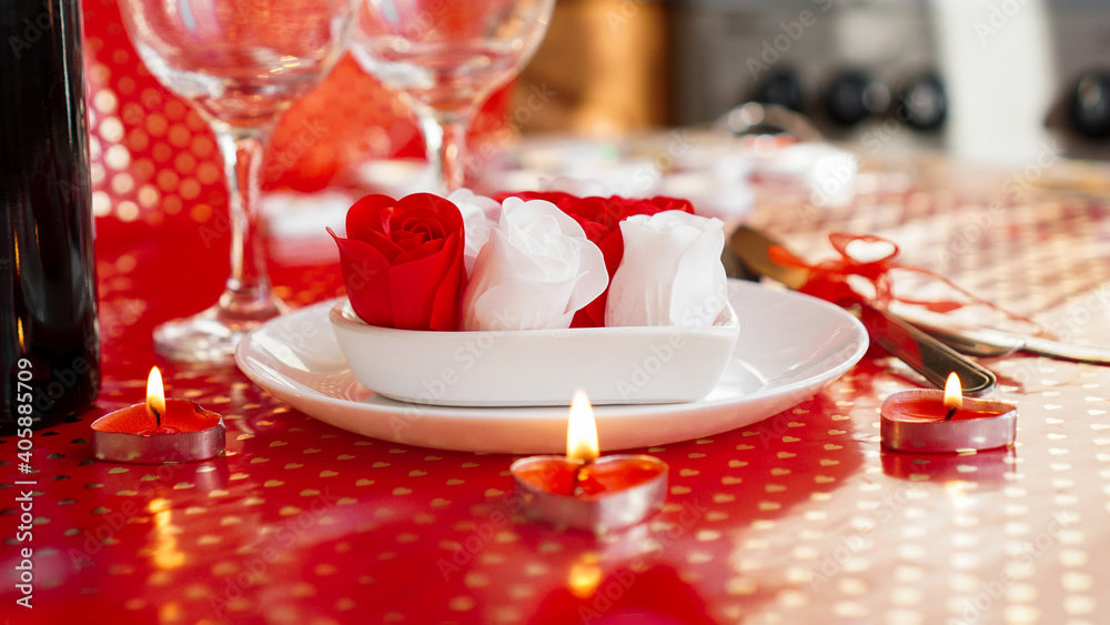Valentines day. Bottle of vine, glasses, red roses, candles - red background. Love dinner concept
