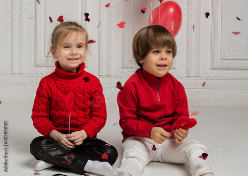 portrait of a boy and a girl sitting on the floor with confetti on a white background
