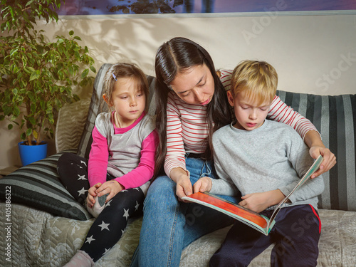 Fotografija Girl nanny reads a book to children