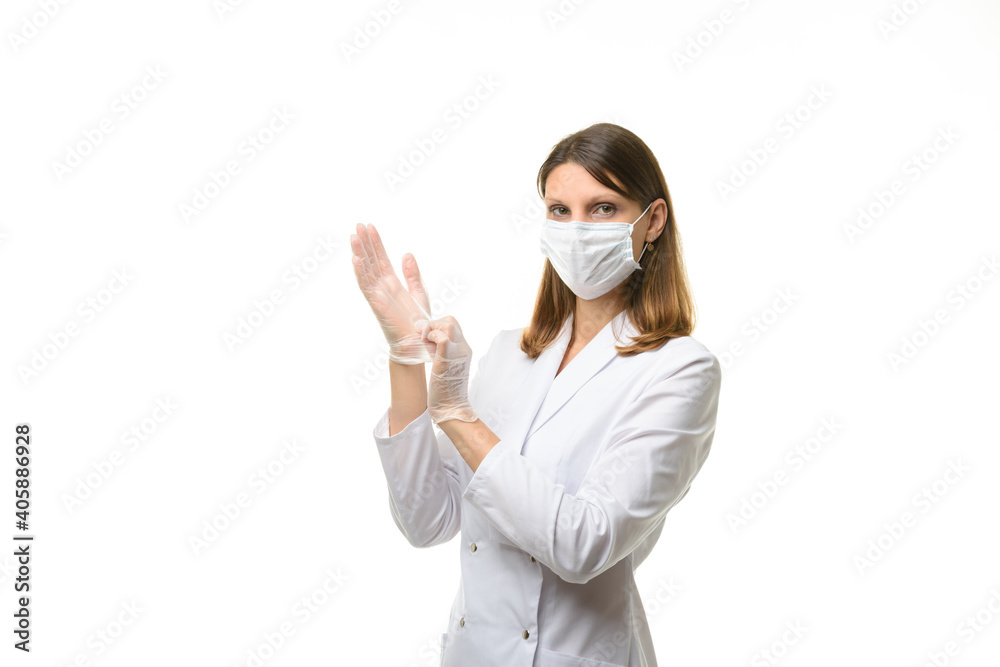 Girl doctor puts on transparent medical gloves on her hands, and looks into the frame Girl doctor puts on transparent medical gloves on her hands, and looks into the frame