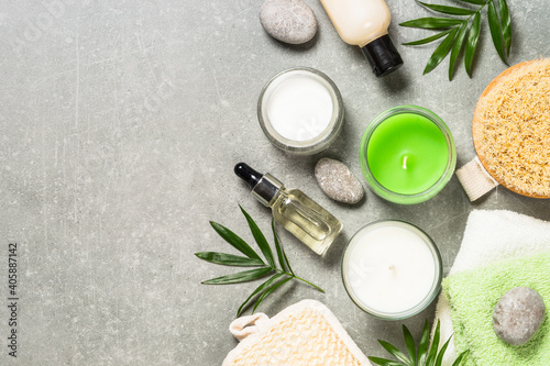 Spa product composition with cosmetics, sea salt, towel and palm leaves at stone table. Flat lay image with copy space.